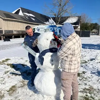 Two Choice Plumbers staff outside the shop building a snowman out of pipe fittings